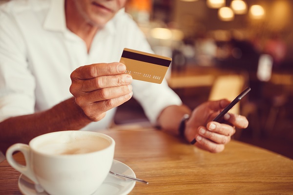 Mann med kaffekopp og bankkort på kafe